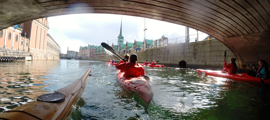 Group of kayaks sailing under a bridge